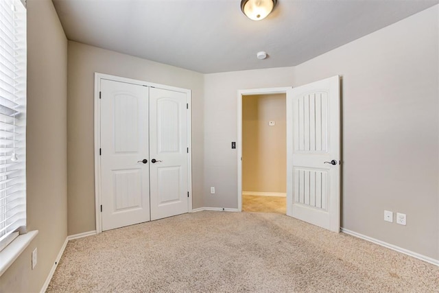 unfurnished bedroom with carpet floors, a closet, and baseboards