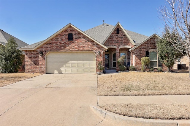 view of front of house with driveway, brick siding, roof with shingles, and an attached garage