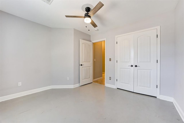 unfurnished bedroom with a ceiling fan, a closet, baseboards, and concrete flooring