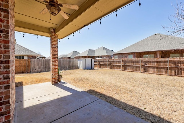 view of patio featuring a ceiling fan, an outbuilding, a fenced backyard, and a shed