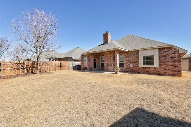 rear view of house with a fenced backyard, a chimney, a patio, and brick siding