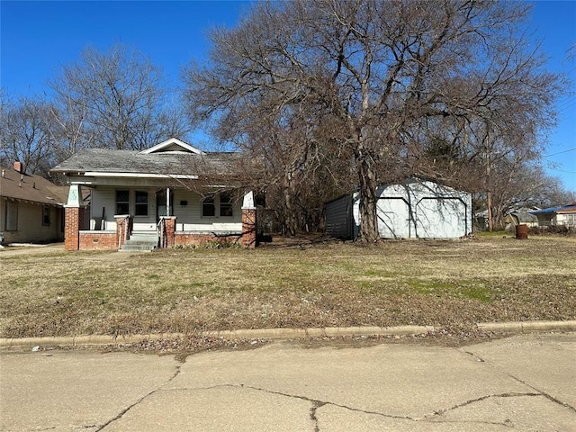 view of front of property with a garage, an outbuilding, covered porch, and a front yard