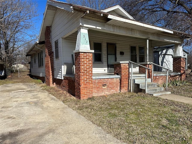 bungalow-style home with brick siding and covered porch