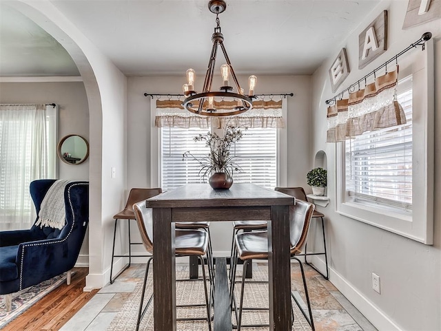 dining area featuring an inviting chandelier, baseboards, arched walkways, and a wealth of natural light