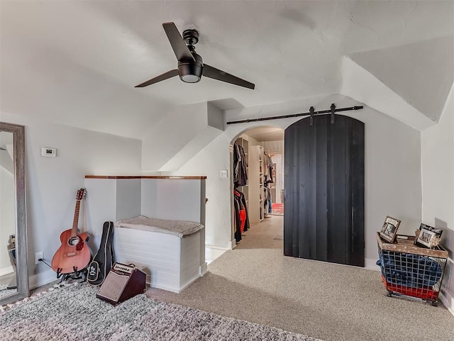 bonus room featuring carpet, a barn door, vaulted ceiling, arched walkways, and a ceiling fan