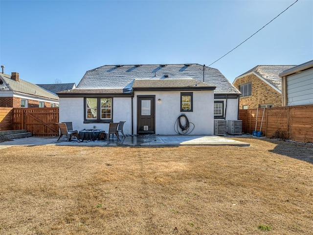 rear view of house featuring a patio, a yard, a fenced backyard, and stucco siding