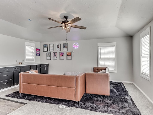 living room featuring ceiling fan, lofted ceiling, baseboards, and carpet floors