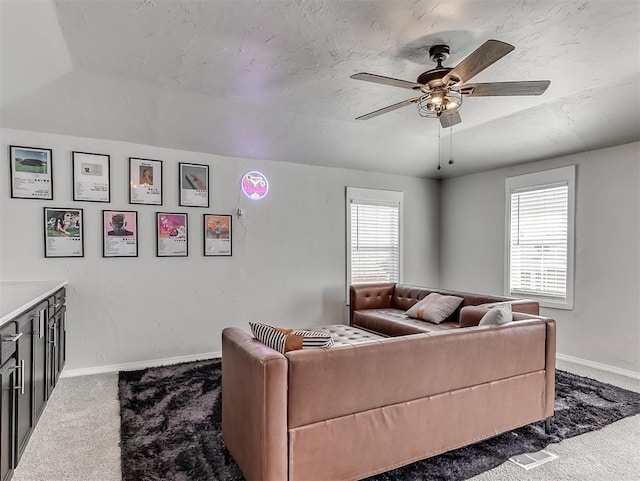 carpeted living area featuring baseboards, plenty of natural light, a textured ceiling, and ceiling fan