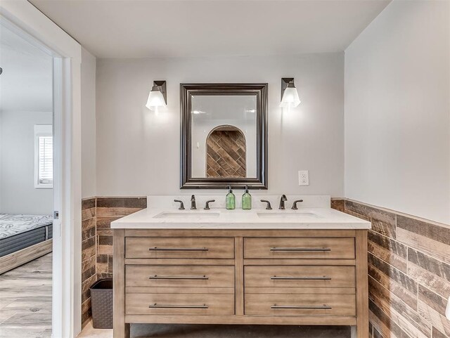 full bath with a sink, tile walls, wainscoting, and double vanity