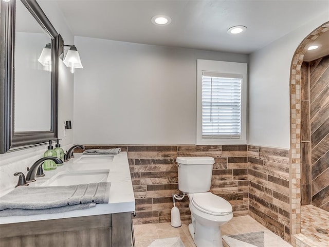 full bath with a sink, toilet, tile walls, and wainscoting