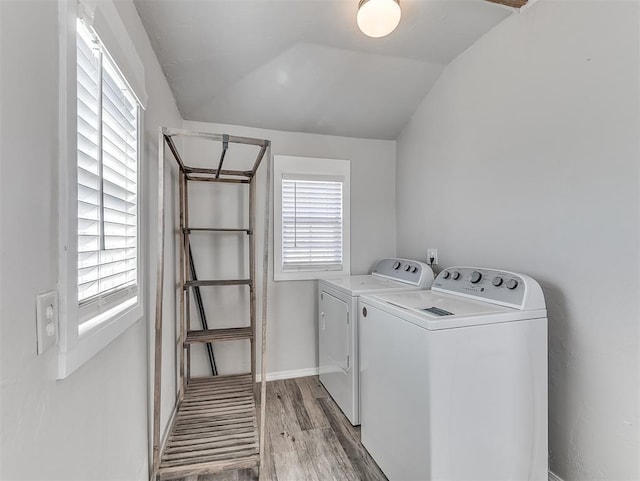 clothes washing area with a wealth of natural light, laundry area, wood finished floors, and separate washer and dryer