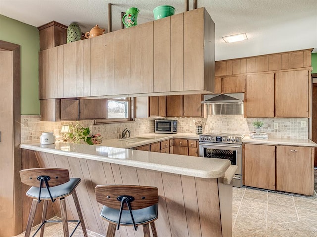 1802 N 15th St, Perry, OK 73077 - kitchen featuring stainless steel appliances, a peninsula, light countertops, tasteful backsplash, and a kitchen breakfast bar