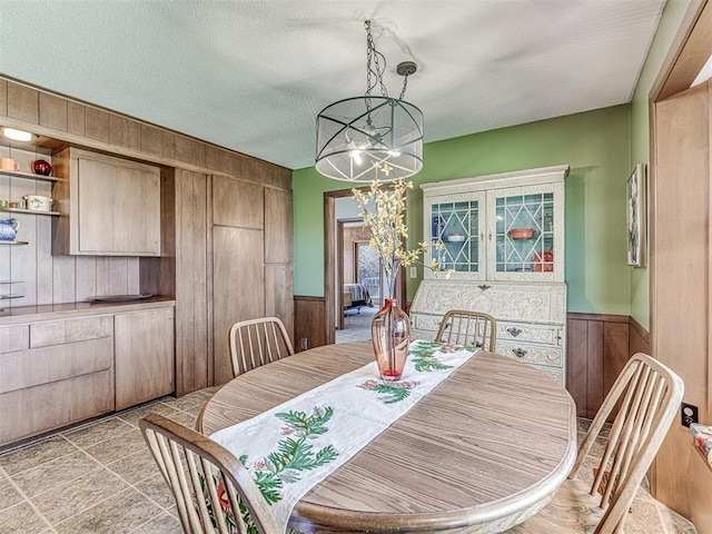 1802 N 15th St, Perry, OK 73077 - dining room featuring wood walls, a chandelier, a textured ceiling, and wainscoting