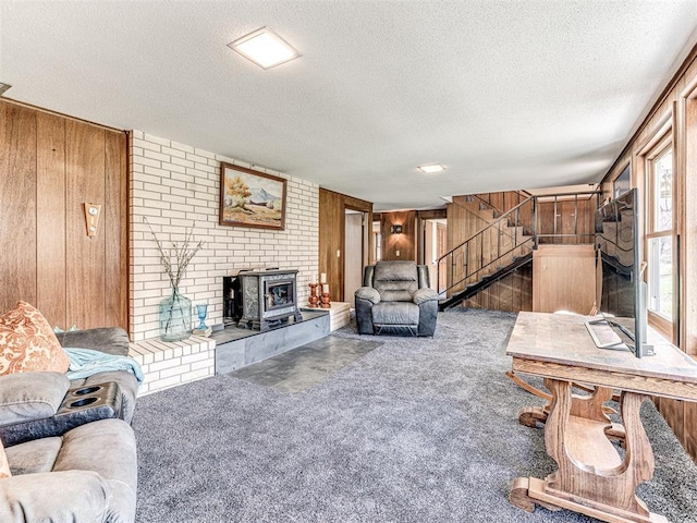 1802 N 15th St, Perry, OK 73077 - carpeted living area with wood walls, a wood stove, a textured ceiling, and stairs