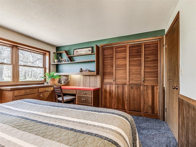1802 N 15th St, Perry, OK 73077 - carpeted bedroom featuring built in desk, a textured ceiling, a closet, and wainscoting