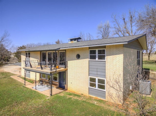 1802 N 15th St, Perry, OK 73077 - rear view of property featuring brick siding, a patio area, a lawn, and roof with shingles