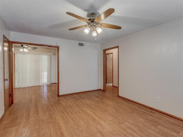 unfurnished room with a textured ceiling, light wood-style flooring, visible vents, and baseboards