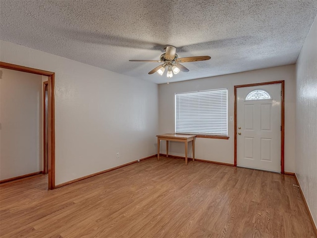 entryway featuring light wood-style flooring, a textured ceiling, baseboards, and a ceiling fan