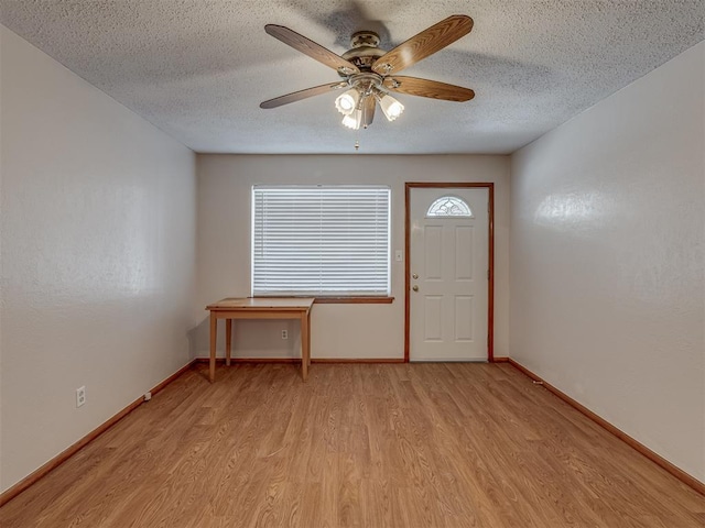 entrance foyer featuring light wood-style floors, a ceiling fan, baseboards, and a textured ceiling