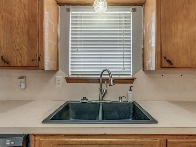 kitchen with brown cabinetry, light countertops, and a sink