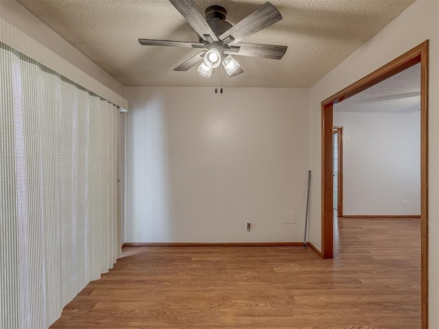 unfurnished room with a textured ceiling, light wood-type flooring, a ceiling fan, and baseboards