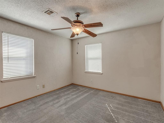 unfurnished room featuring light carpet, a textured ceiling, visible vents, and a ceiling fan