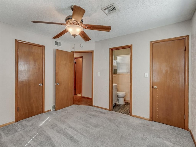 unfurnished bedroom featuring light carpet, visible vents, and a textured ceiling