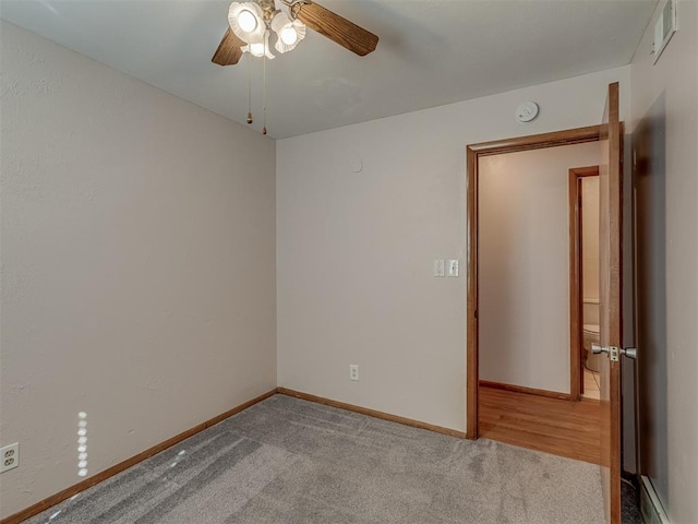 carpeted empty room featuring a baseboard radiator, a ceiling fan, and baseboards