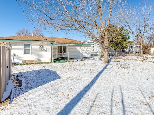 snow covered rear of property with fence