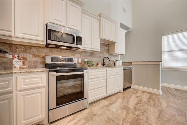 kitchen with appliances with stainless steel finishes, backsplash, baseboards, and light stone countertops