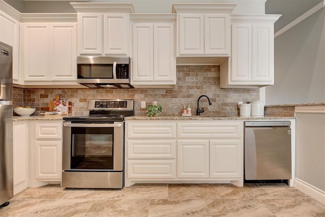 kitchen featuring light stone counters, a sink, white cabinetry, appliances with stainless steel finishes, and tasteful backsplash