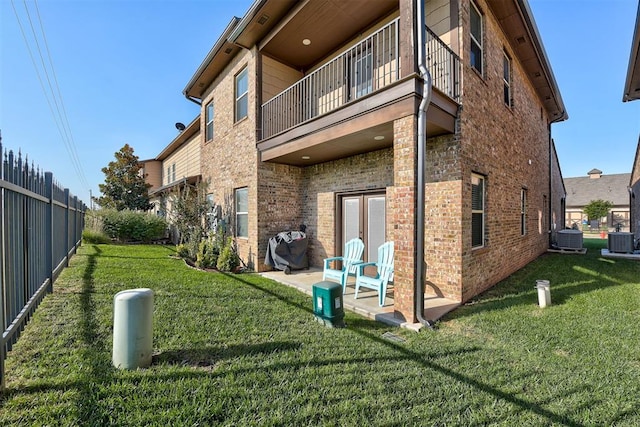 rear view of property with brick siding, central AC unit, fence, and a balcony