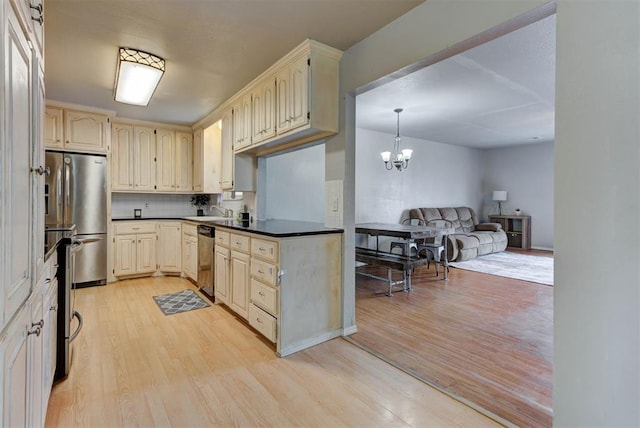 kitchen featuring a chandelier, stainless steel appliances, open floor plan, light wood-type flooring, and dark countertops