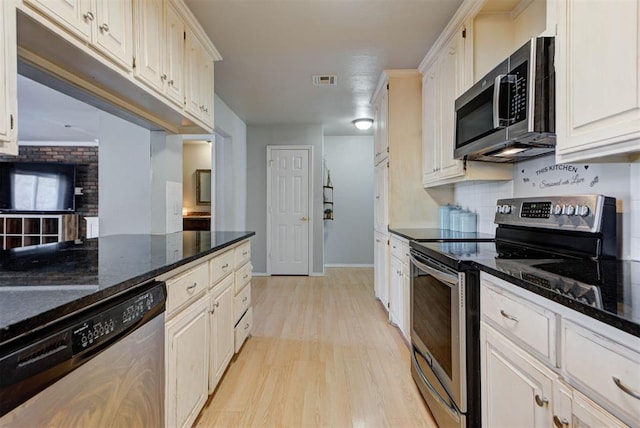 kitchen with stainless steel appliances, visible vents, decorative backsplash, dark stone countertops, and light wood-type flooring