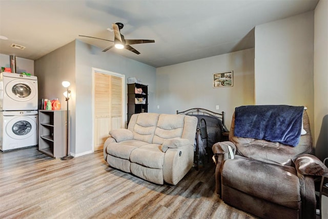 living area with light wood-style floors, stacked washer / dryer, ceiling fan, and baseboards