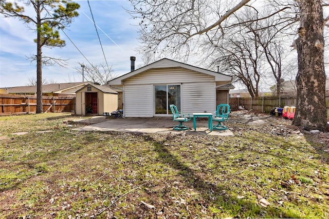 back of property featuring an outbuilding, a yard, a storage shed, a patio area, and a fenced backyard