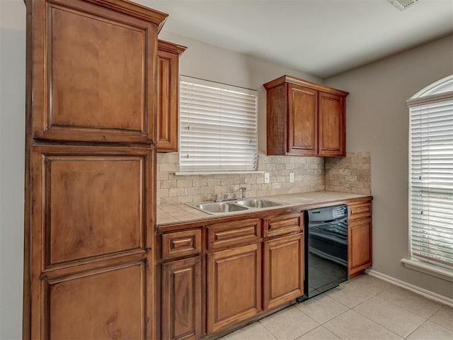 kitchen with light tile patterned flooring, sink, black dishwasher, and backsplash