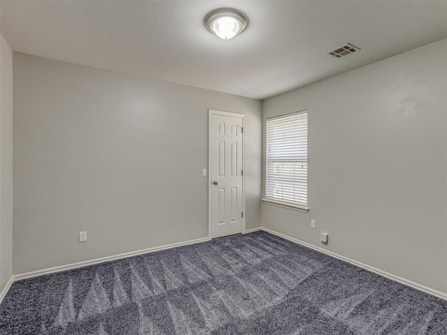 spare room featuring dark colored carpet