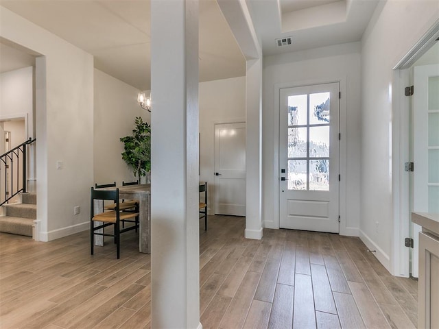 entryway with wood finish floors, visible vents, baseboards, and stairs