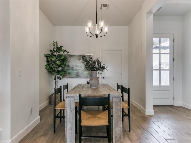 dining room with light wood finished floors, visible vents, and baseboards