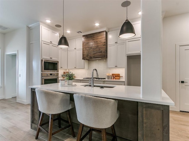 kitchen with white cabinets, built in microwave, light countertops, stainless steel oven, and pendant lighting