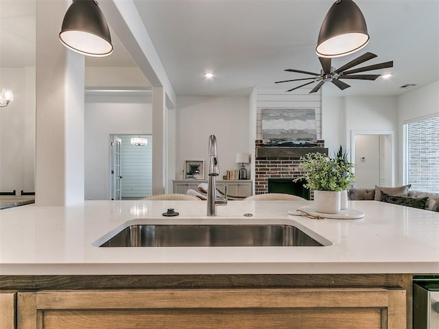 kitchen featuring beverage cooler, ceiling fan with notable chandelier, a sink, open floor plan, and a brick fireplace