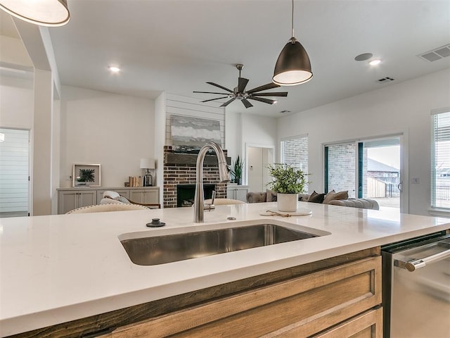 kitchen featuring a sink, visible vents, open floor plan, stainless steel dishwasher, and pendant lighting