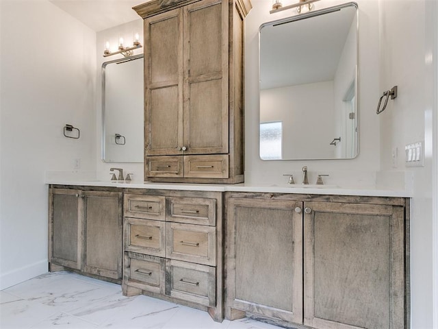 full bathroom featuring marble finish floor, double vanity, a sink, and baseboards