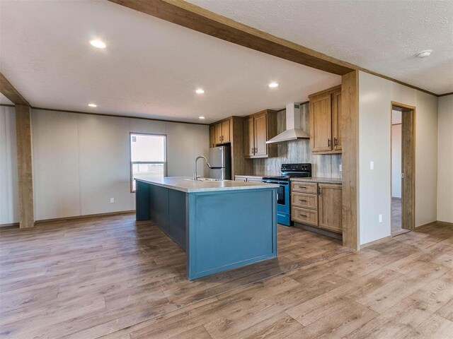 28992 Oakwood Meadows Dr, Cashion, OK 73016 - kitchen featuring electric range oven, an island with sink, stainless steel fridge, light hardwood / wood-style flooring, and wall chimney exhaust hood