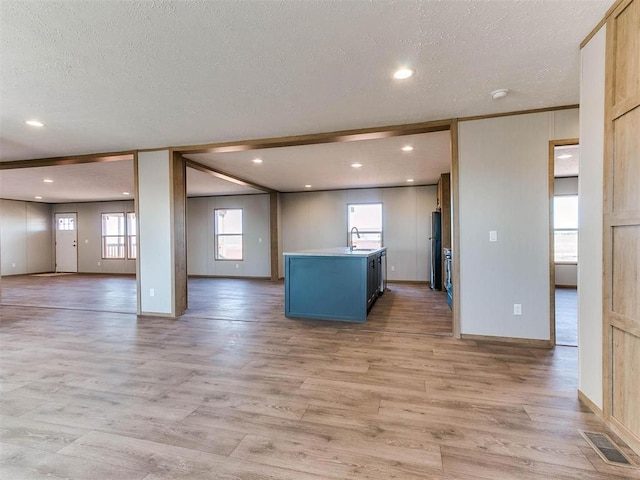 28992 Oakwood Meadows Dr, Cashion, OK 73016 - kitchen featuring stainless steel refrigerator, a textured ceiling, light wood-type flooring, a center island with sink, and sink