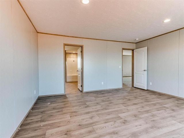 28992 Oakwood Meadows Dr, Cashion, OK 73016 - unfurnished bedroom featuring a textured ceiling, connected bathroom, crown molding, and light hardwood / wood-style floors