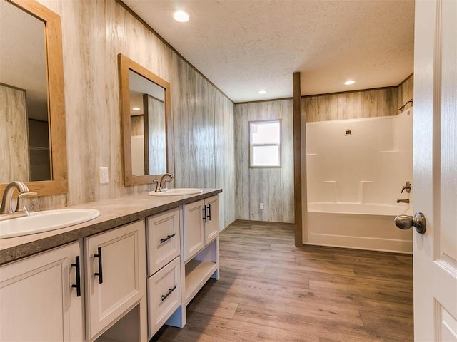 28992 Oakwood Meadows Dr, Cashion, OK 73016 - bathroom featuring hardwood / wood-style floors, vanity, wood walls, a textured ceiling, and bathtub / shower combination