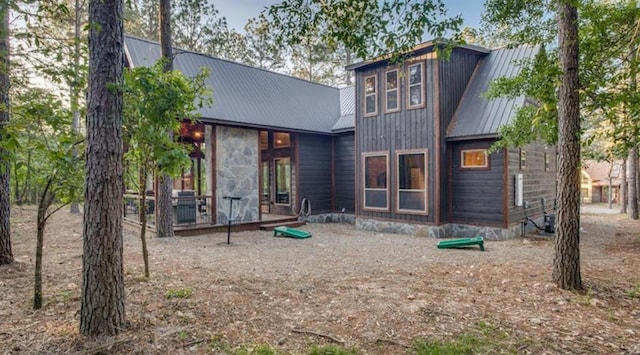 back of house with metal roof and central AC unit