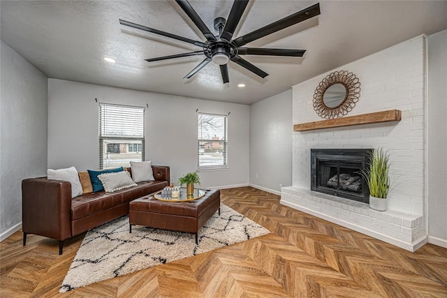 living room featuring baseboards, a ceiling fan, a textured ceiling, a brick fireplace, and recessed lighting